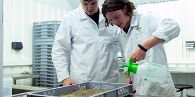 Photo of two engineers watering plants in a lab