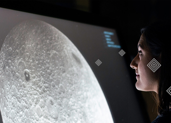 Picture of a female engineer looking at a large image of the moon